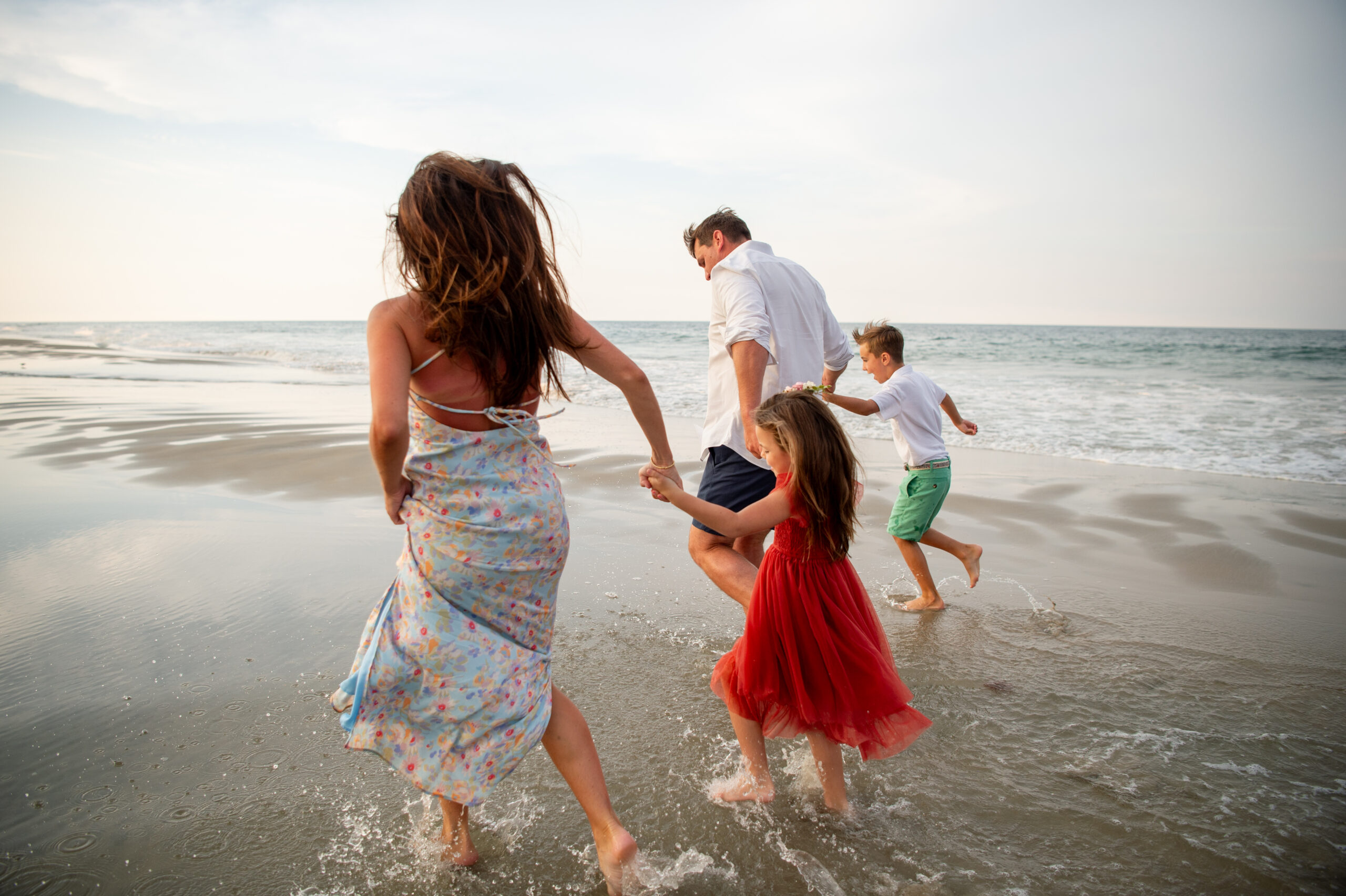 family running through the water at beach