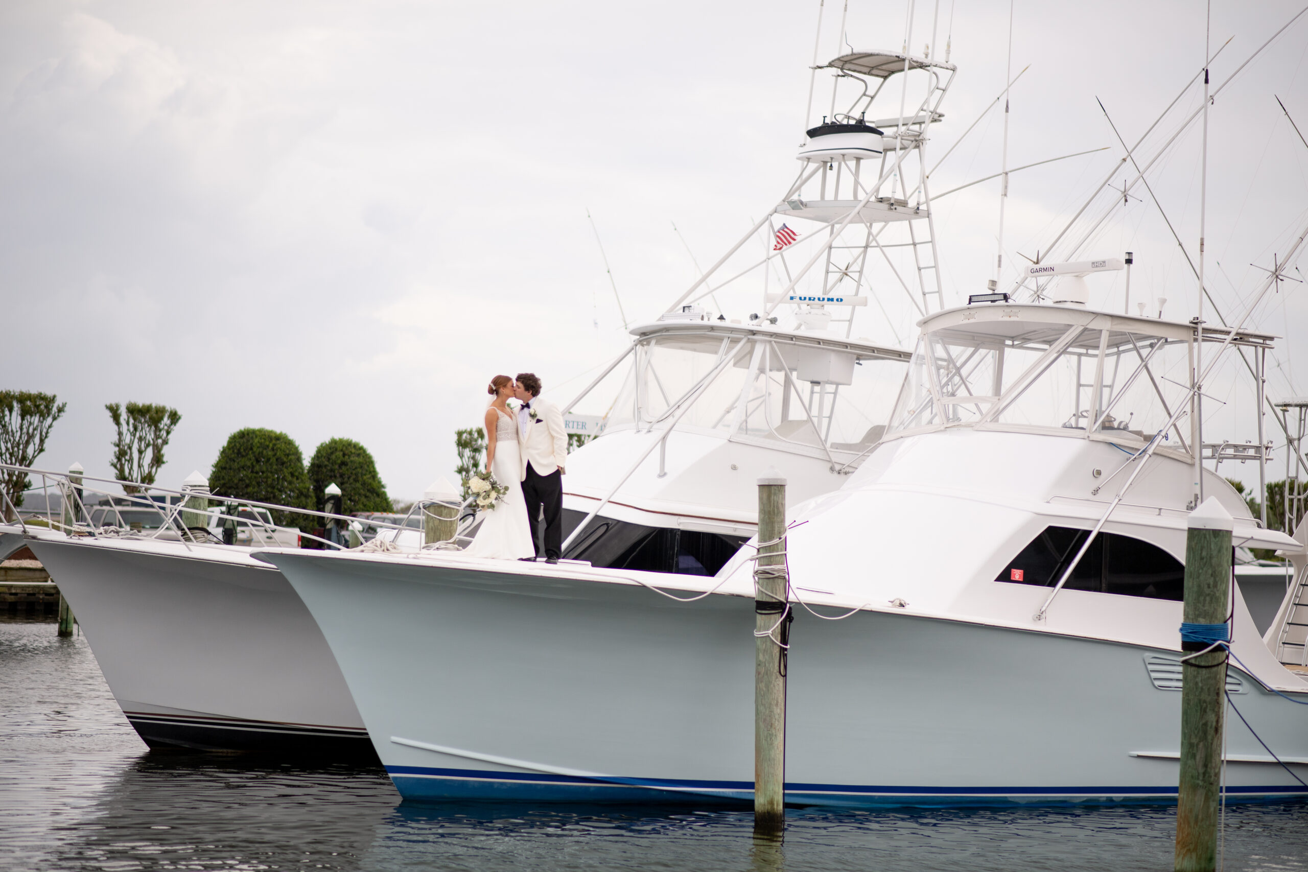 Bride and Groom kissing standing on fishing yacht at Pirate's Cove Marina in Manteo, NC on their wedding day.