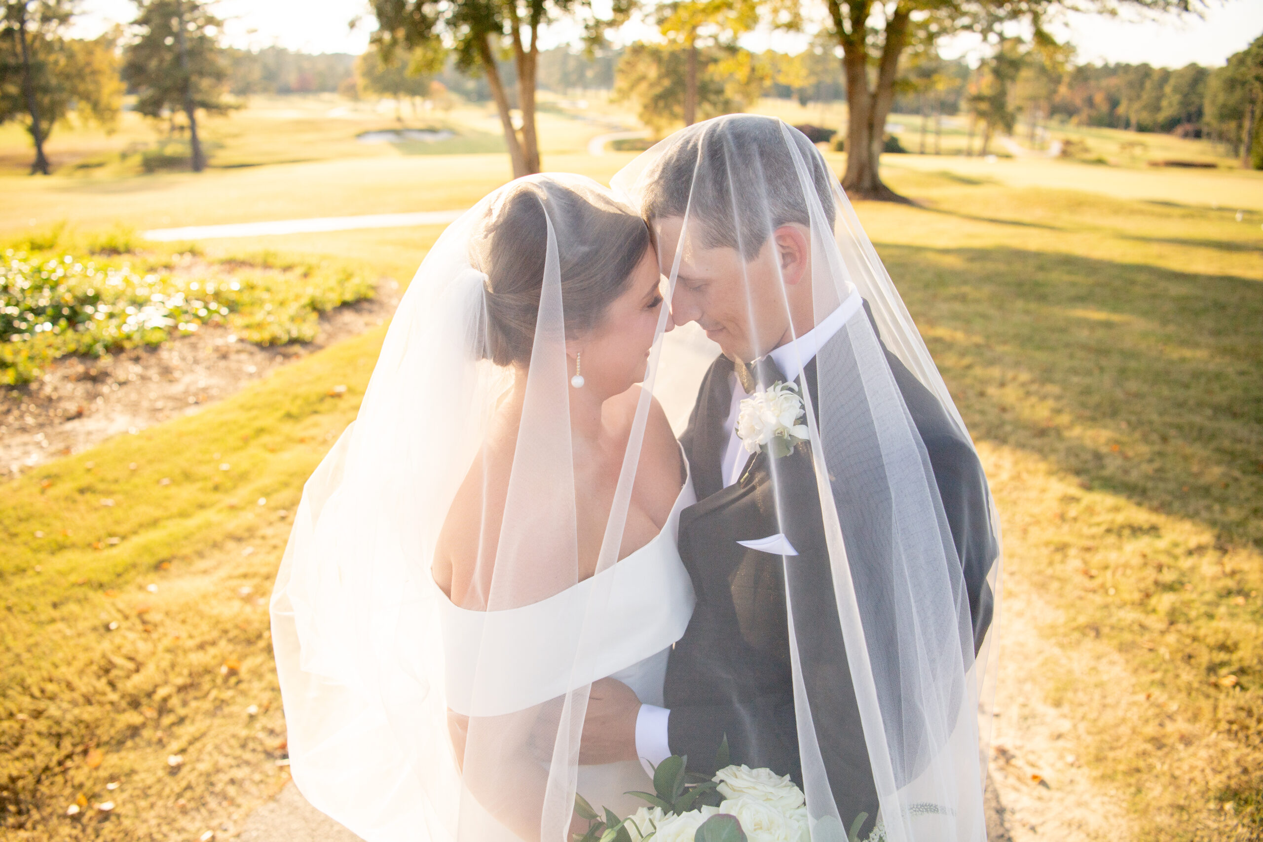 Bride and Groom snuggle under veil.