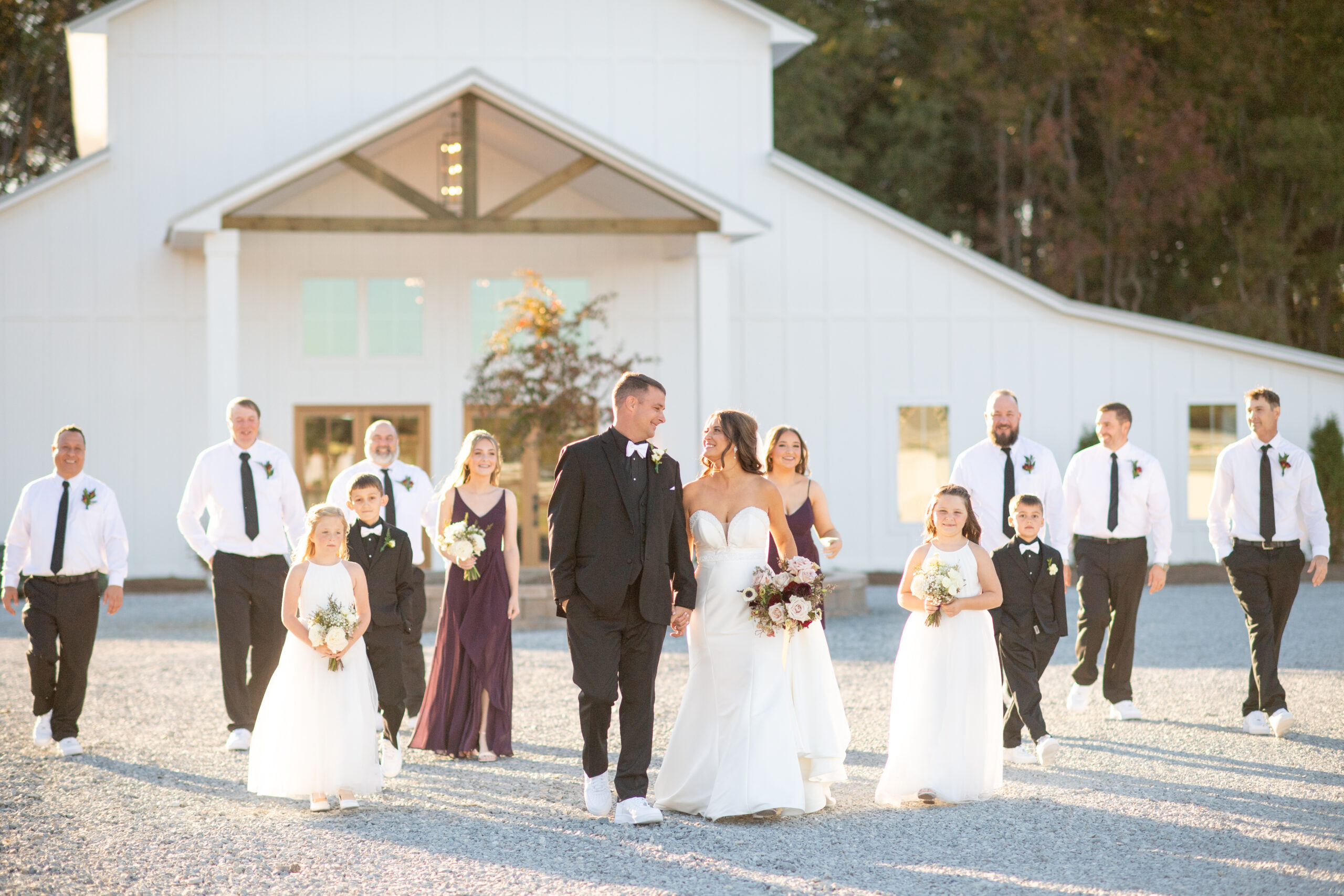 Bride and Groom walking in golden light with wedding party in front of The Hartwood Weddings and Events Venue in Selma, NC