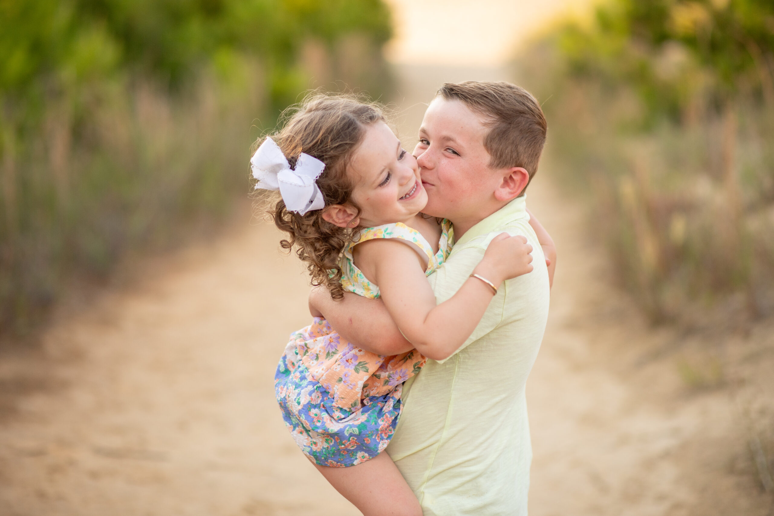 Big brother kissing little sister on the cheek during sweet OBX beach family session.